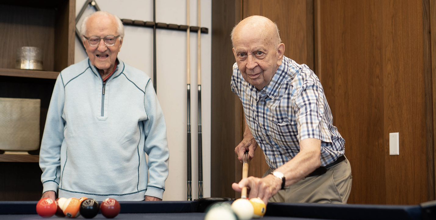 Two senior men playing pool with one about to take a shot