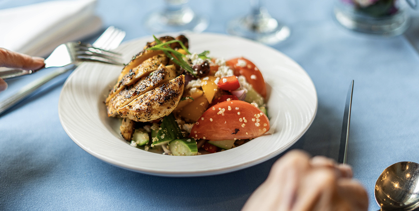 a healthy and delicious plat of grilled chicken with a greek village salad